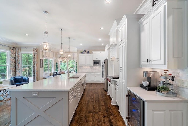 kitchen featuring light countertops, beverage cooler, stainless steel appliances, decorative backsplash, and a center island with sink