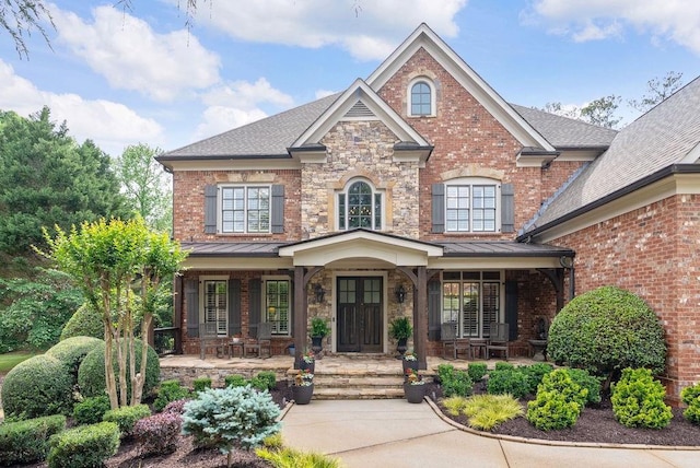 craftsman inspired home featuring a porch, a shingled roof, brick siding, and a standing seam roof