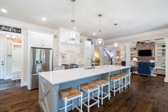 kitchen featuring crown molding, stove, a sink, open floor plan, and stainless steel fridge