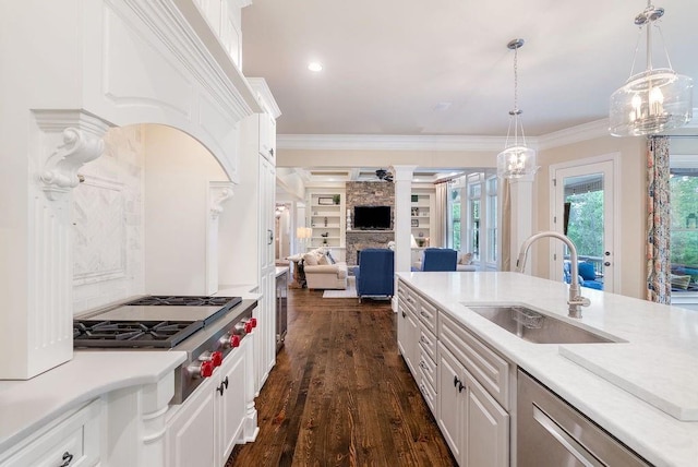 kitchen with a stone fireplace, open floor plan, white cabinets, a sink, and stainless steel appliances