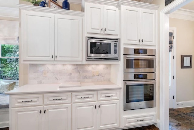 kitchen featuring decorative backsplash, ornamental molding, stainless steel appliances, and white cabinetry