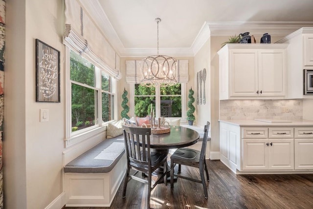 dining room featuring ornamental molding, baseboards, breakfast area, a chandelier, and dark wood finished floors