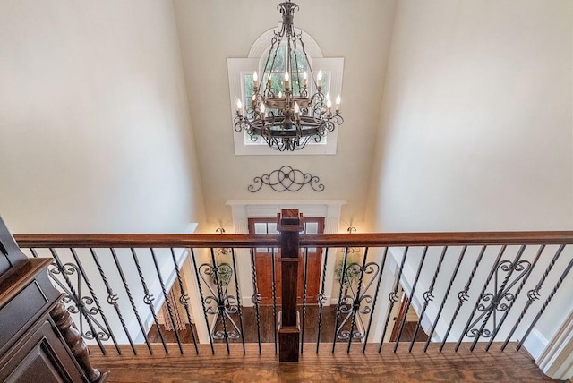 stairs with wood finished floors and a notable chandelier