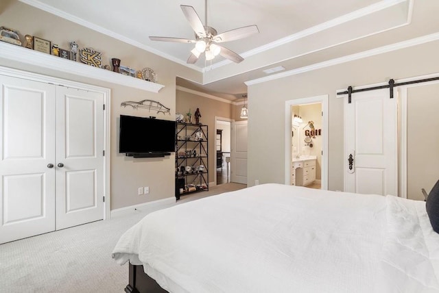carpeted bedroom with connected bathroom, a barn door, baseboards, visible vents, and ornamental molding