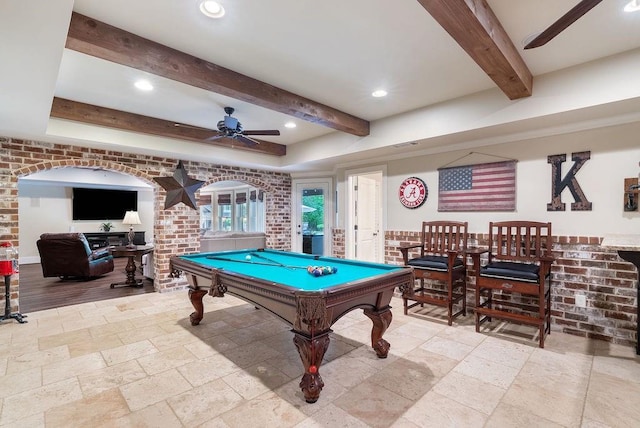 playroom with ceiling fan, pool table, arched walkways, beamed ceiling, and stone tile floors