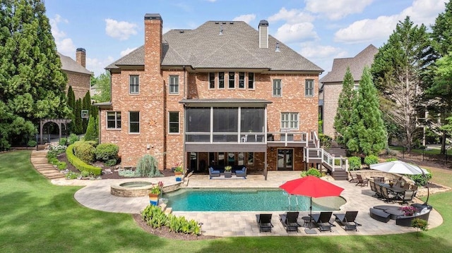 back of property featuring a patio, a chimney, brick siding, a sunroom, and stairway