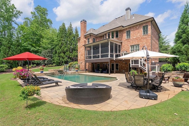 rear view of house featuring brick siding, a chimney, a patio area, and a sunroom