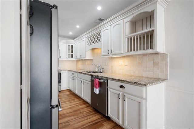 kitchen featuring light stone counters, light wood-style flooring, decorative backsplash, appliances with stainless steel finishes, and white cabinets