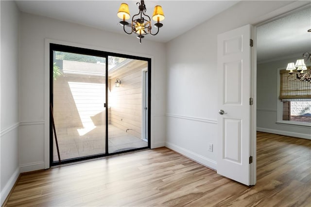 unfurnished room featuring wood finished floors, a wealth of natural light, and a notable chandelier