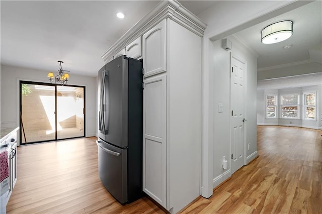 kitchen featuring ornamental molding, freestanding refrigerator, light wood-style floors, white cabinetry, and a notable chandelier