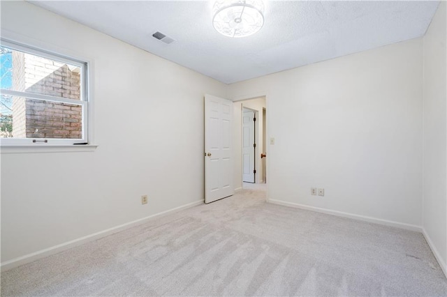 unfurnished room featuring carpet flooring, visible vents, and baseboards