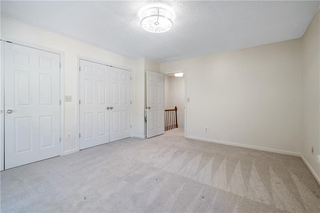 unfurnished bedroom with carpet, a closet, baseboards, and a textured ceiling