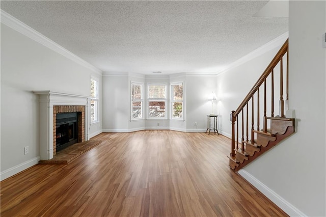 unfurnished living room with stairs, a brick fireplace, ornamental molding, and wood finished floors