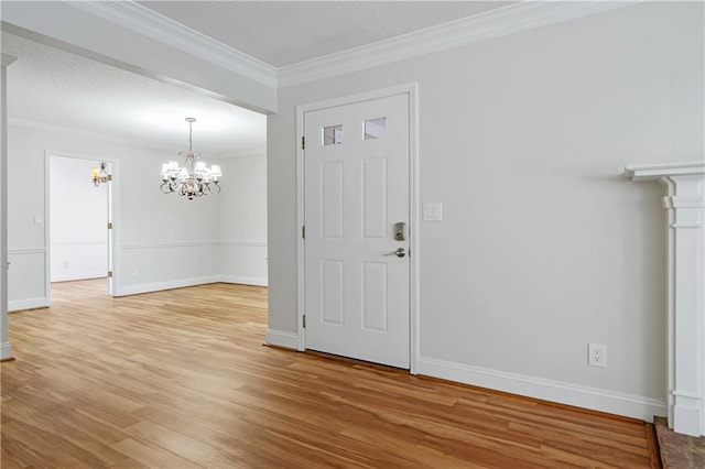 foyer entrance featuring ornamental molding, light wood-type flooring, a textured ceiling, and baseboards