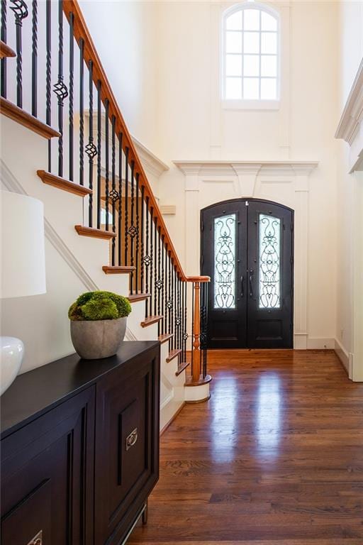 foyer featuring dark wood-type flooring, french doors, and a towering ceiling