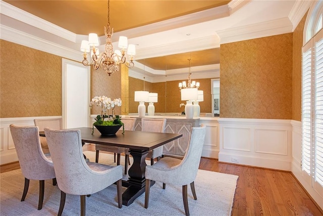 dining space with light hardwood / wood-style floors, crown molding, a tray ceiling, and an inviting chandelier