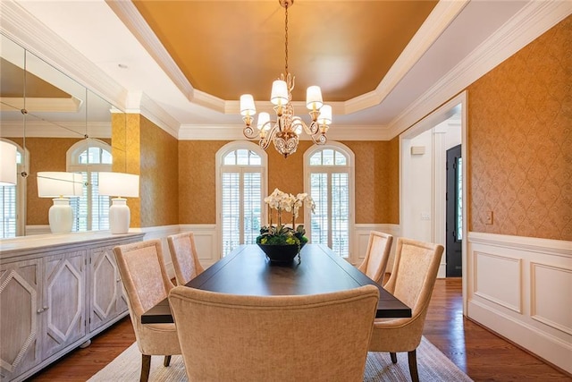 dining area with hardwood / wood-style floors, a chandelier, ornamental molding, and a tray ceiling