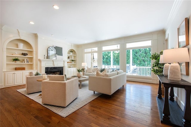 living room featuring ornamental molding, a fireplace, built in features, and dark wood-type flooring