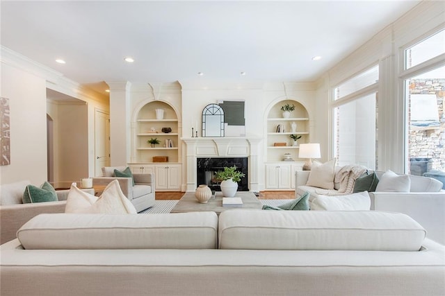 living room featuring hardwood / wood-style floors, a premium fireplace, built in features, and crown molding