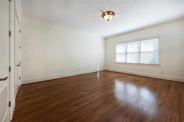 spare room featuring ornamental molding and dark hardwood / wood-style floors