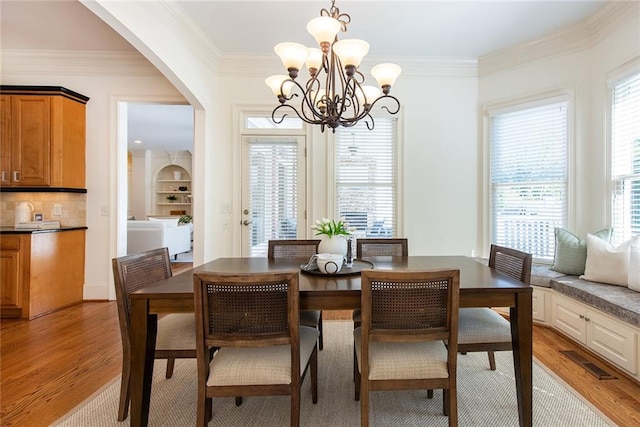 dining room with a chandelier, plenty of natural light, light wood-type flooring, and ornamental molding