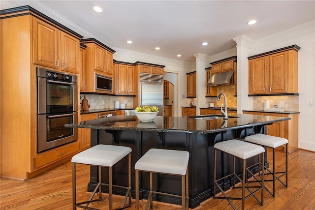 kitchen featuring light wood-type flooring, a large island, a kitchen bar, and built in appliances