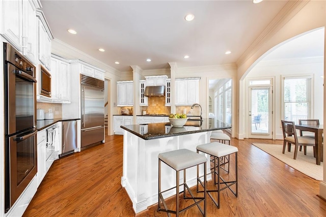 kitchen with built in appliances, light wood-type flooring, and white cabinets