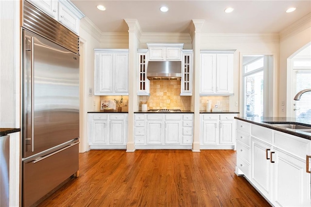 kitchen featuring extractor fan, wood-type flooring, sink, and built in refrigerator