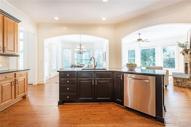 kitchen featuring a stone fireplace, hardwood / wood-style floors, stainless steel dishwasher, and sink