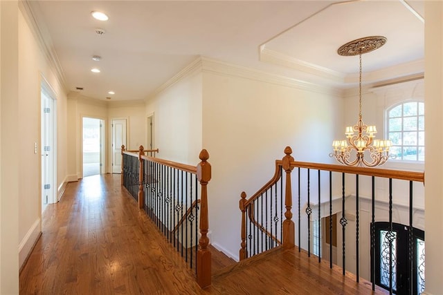 hall with hardwood / wood-style floors, a chandelier, and ornamental molding