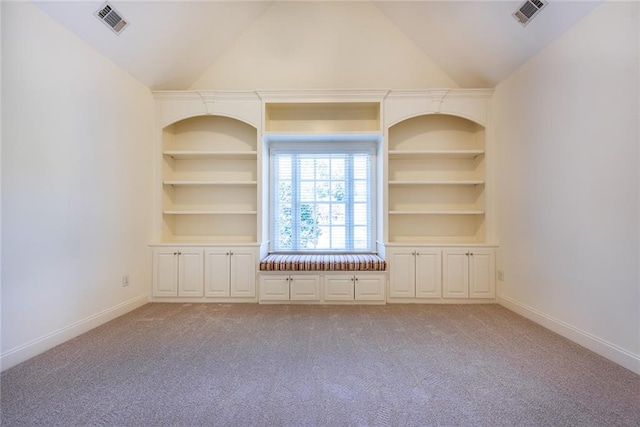 unfurnished living room featuring built in shelves, light colored carpet, and vaulted ceiling