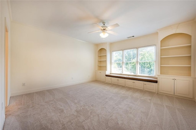 carpeted empty room featuring built in features and ceiling fan