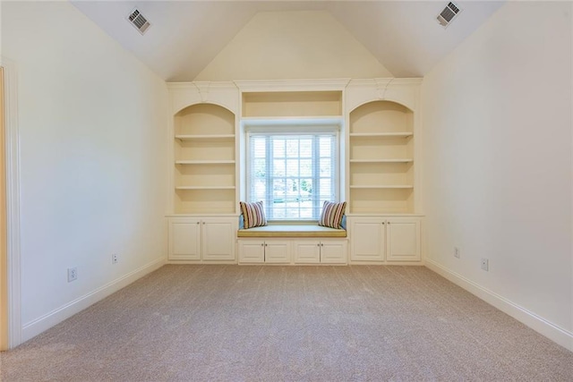 unfurnished room with built in features, vaulted ceiling, and light colored carpet