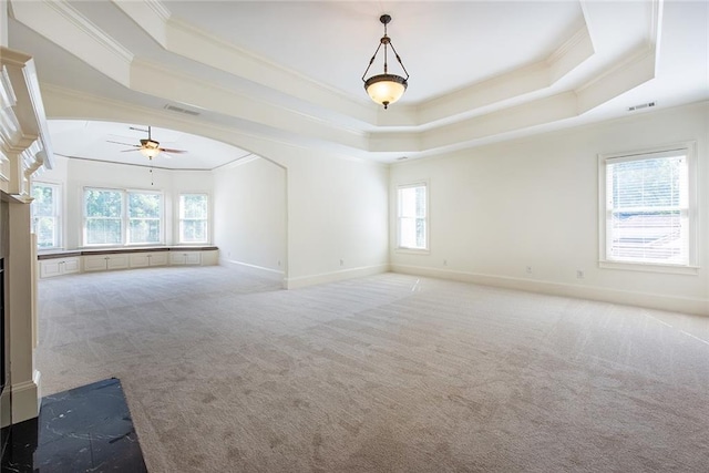 spare room with a tray ceiling, carpet flooring, ceiling fan, and crown molding