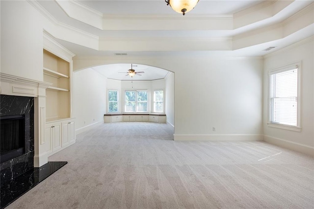 unfurnished living room featuring ornamental molding, ceiling fan, light colored carpet, and a healthy amount of sunlight