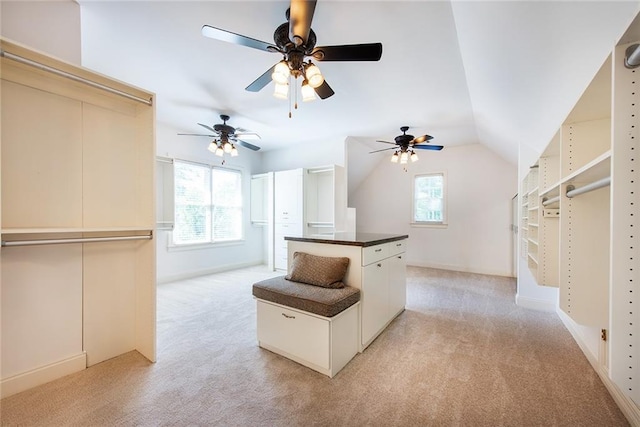 walk in closet with light colored carpet, ceiling fan, and vaulted ceiling