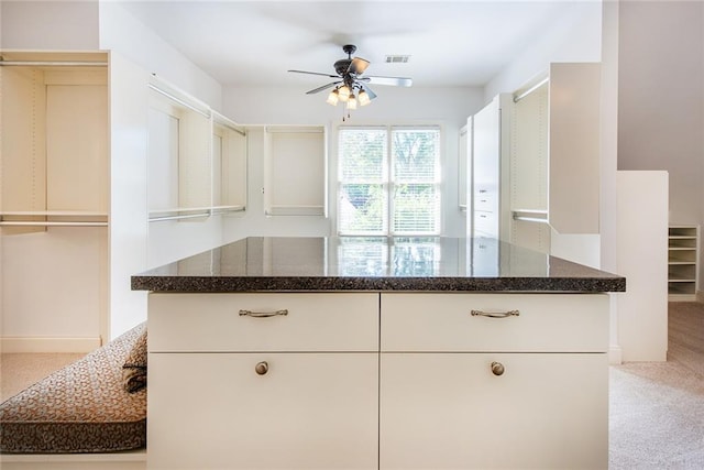 kitchen with white cabinets, ceiling fan, and light carpet