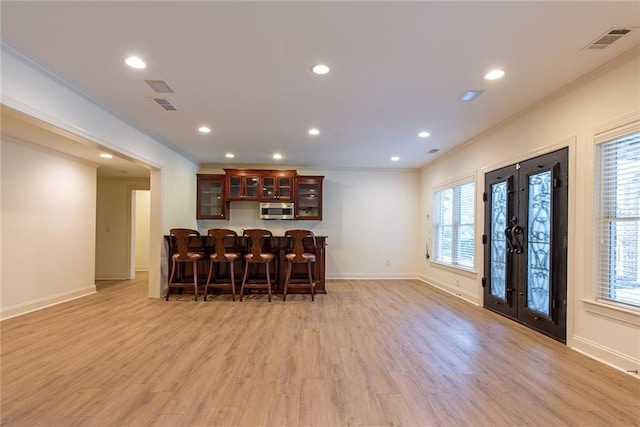 bar featuring light wood-type flooring, a wealth of natural light, and crown molding