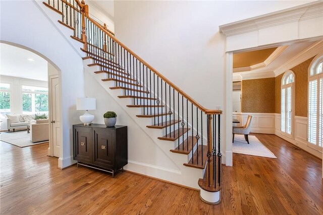 stairs featuring wood-type flooring and ornamental molding