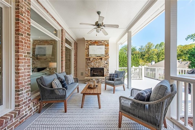 sunroom / solarium featuring ceiling fan and an outdoor stone fireplace