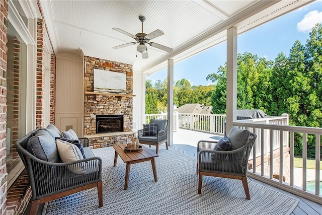 sunroom / solarium featuring a stone fireplace and ceiling fan