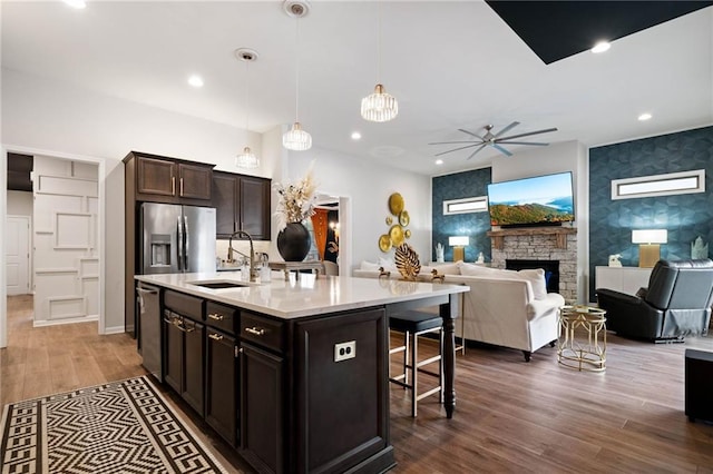 kitchen featuring an accent wall, a breakfast bar, appliances with stainless steel finishes, a fireplace, and dark wood-style floors