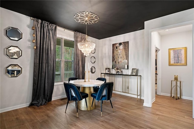 dining area featuring a chandelier, baseboards, and wood finished floors