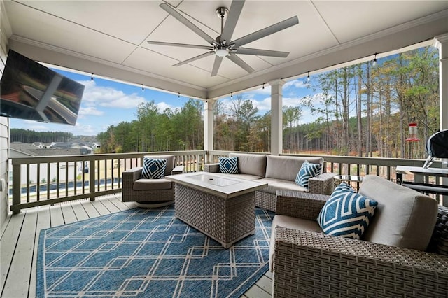 wooden deck with outdoor lounge area and a ceiling fan