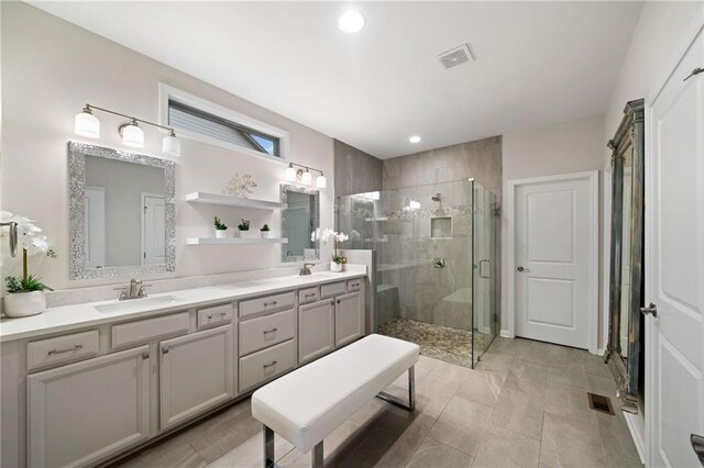 full bath with a sink, visible vents, double vanity, and a shower stall