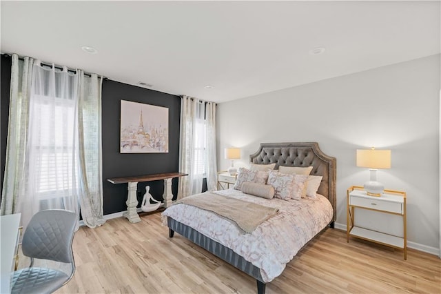 bedroom with visible vents, baseboards, and wood finished floors