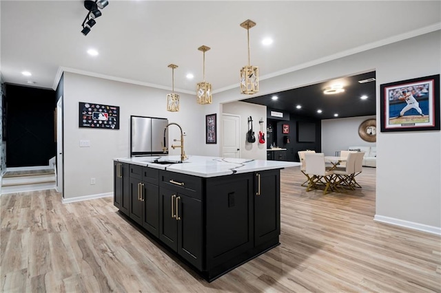 kitchen featuring crown molding, baseboards, dark cabinetry, light wood-style floors, and a sink