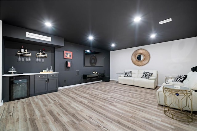 living area featuring wine cooler, recessed lighting, light wood-style flooring, and a dry bar