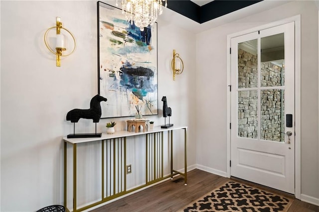 doorway to outside featuring an inviting chandelier, wood finished floors, and baseboards