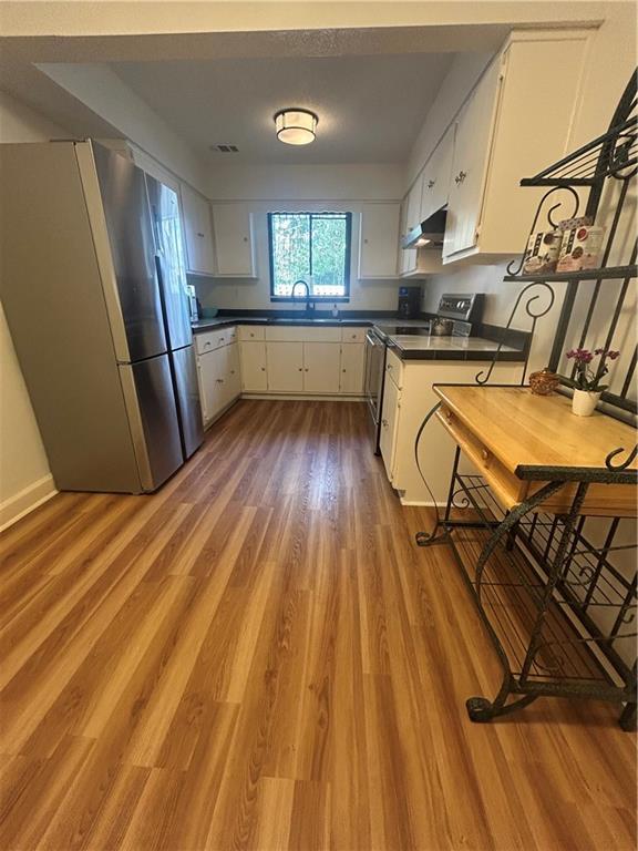 kitchen with dark countertops, freestanding refrigerator, and wood finished floors